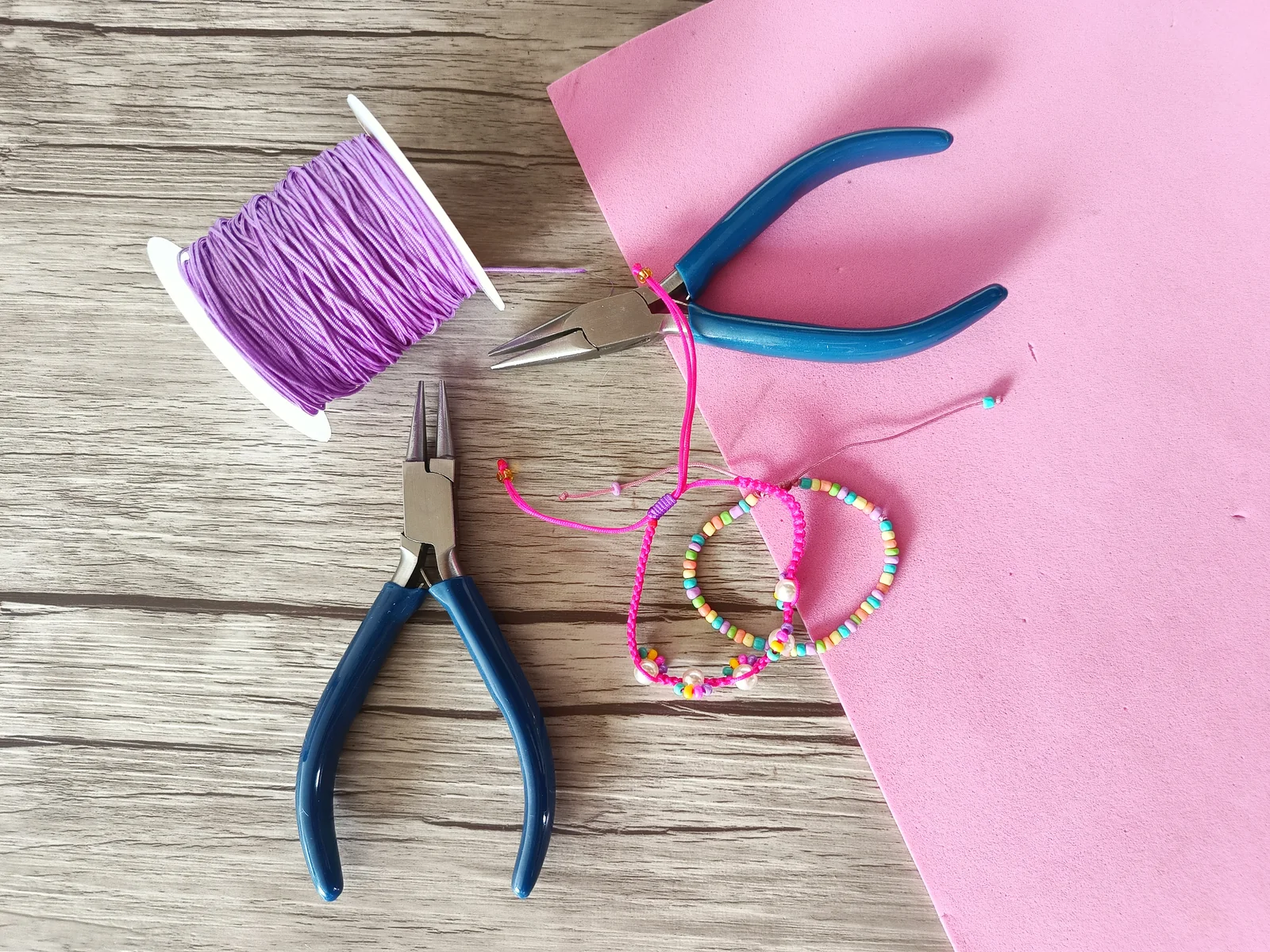 Mesa de proceso con alicates, hilo y pulseras del material oficial del curso