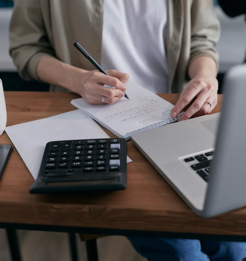 Educación financiera en la escuela: 7 claves esenciales 4 Persona calcula un presupuesto con una calculadora y un cuaderno