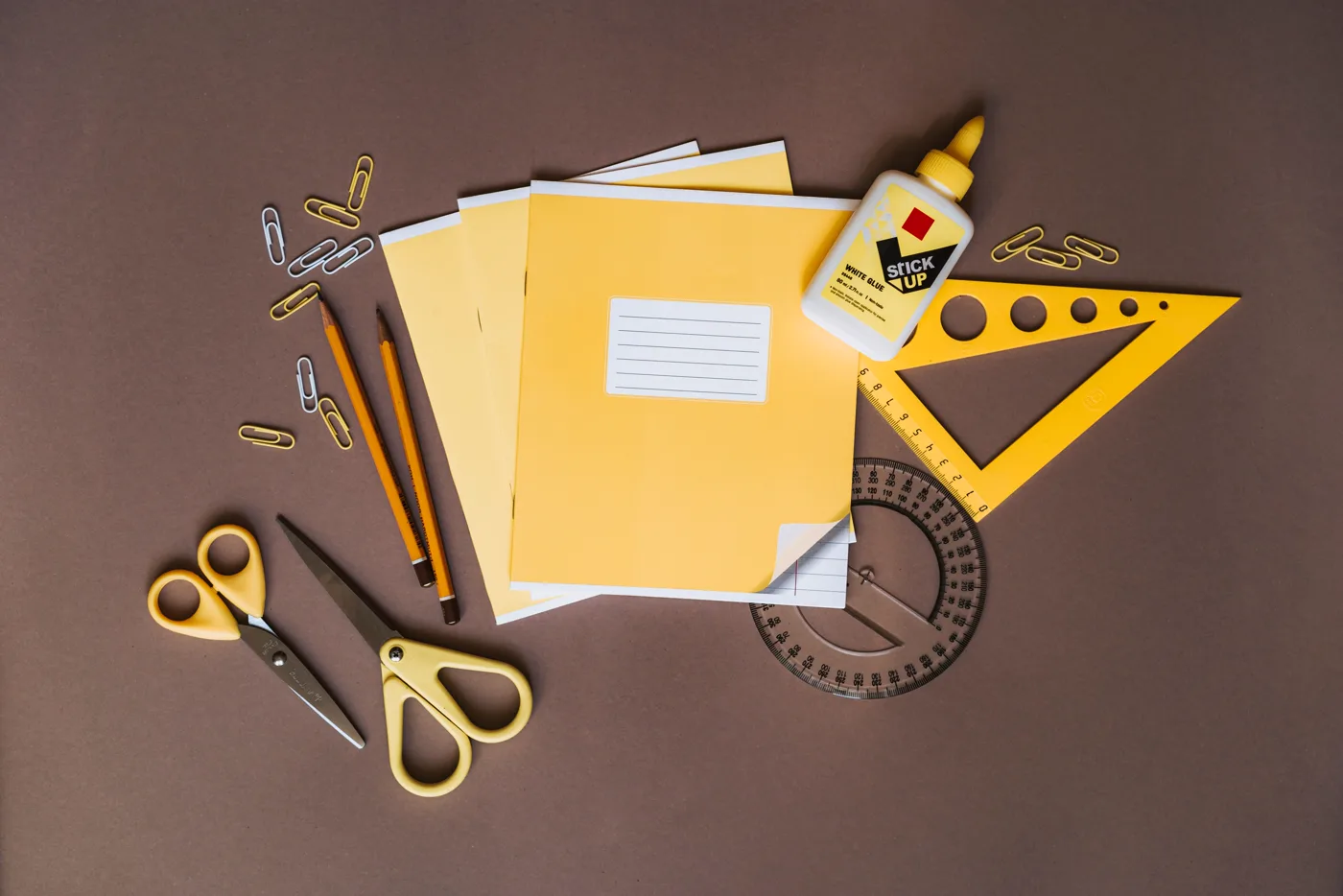 Materiales para papelería creativa: papel, lápices, tijeras, útiles de medición y cola sobre una mesa