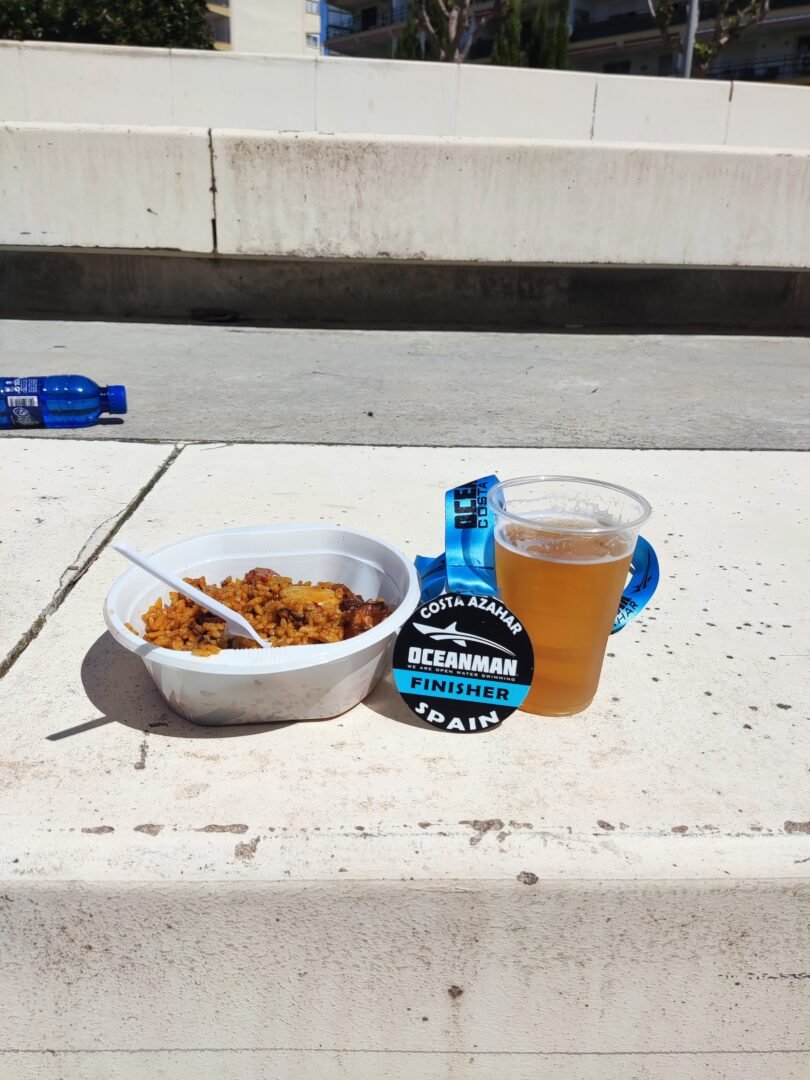 ¿Cómo puede la motivación personal ayudarte a alcanzar tus metas? 4 medalla conseguida en Oceanman costa de azahar 2022 con un buen plato de paella y una cerveza para celebrarlo.ex