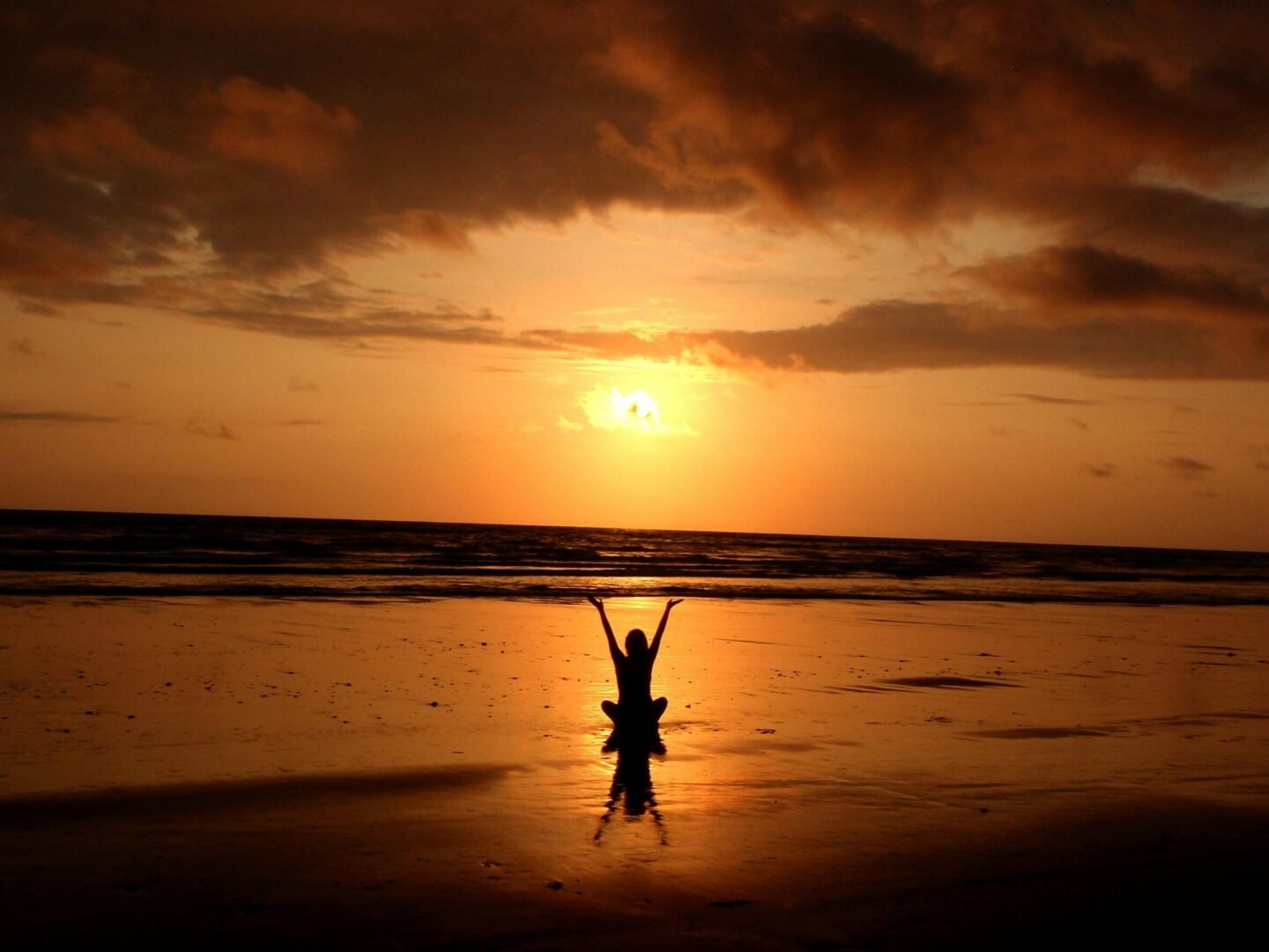 Peaceful meditation silhouette at sunset on a serene beach.