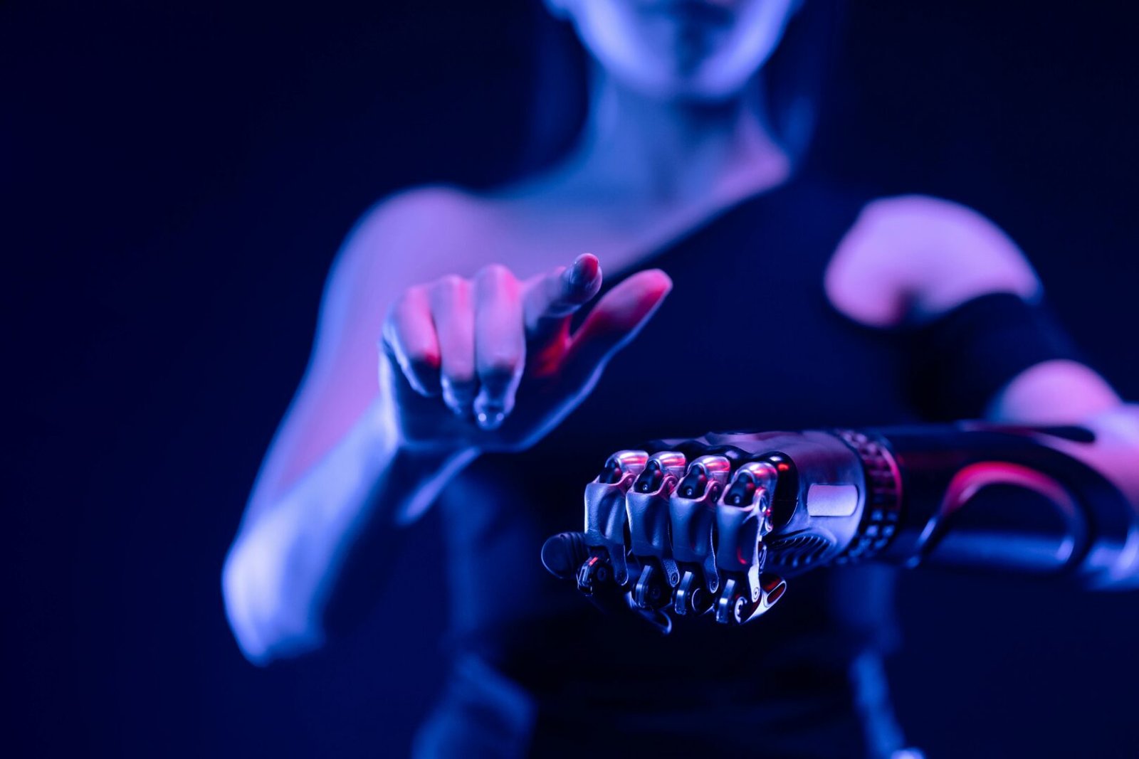 Close-up of a robotic hand with a woman pointing, showcasing advanced prosthetic technology.