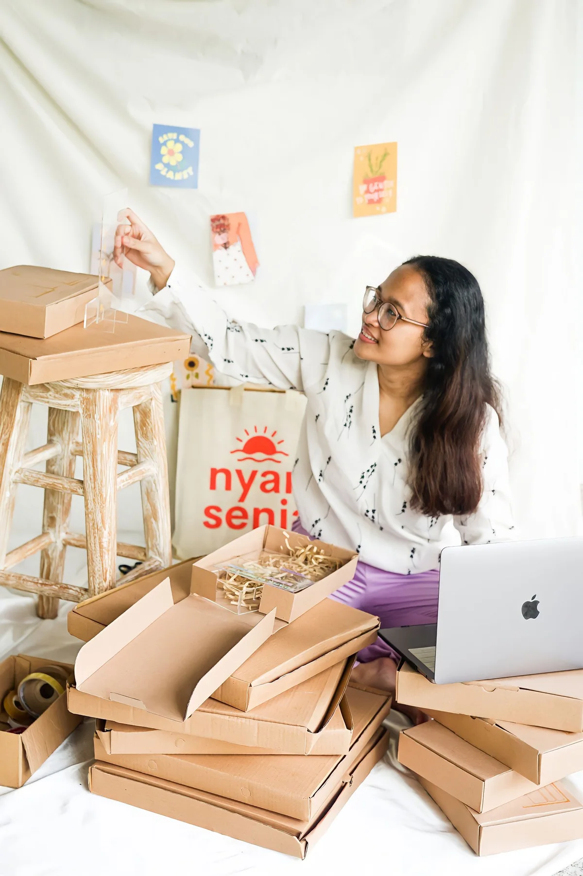 Emprendedora preparando pedidos de su pequeña tienda online junto a un portátil