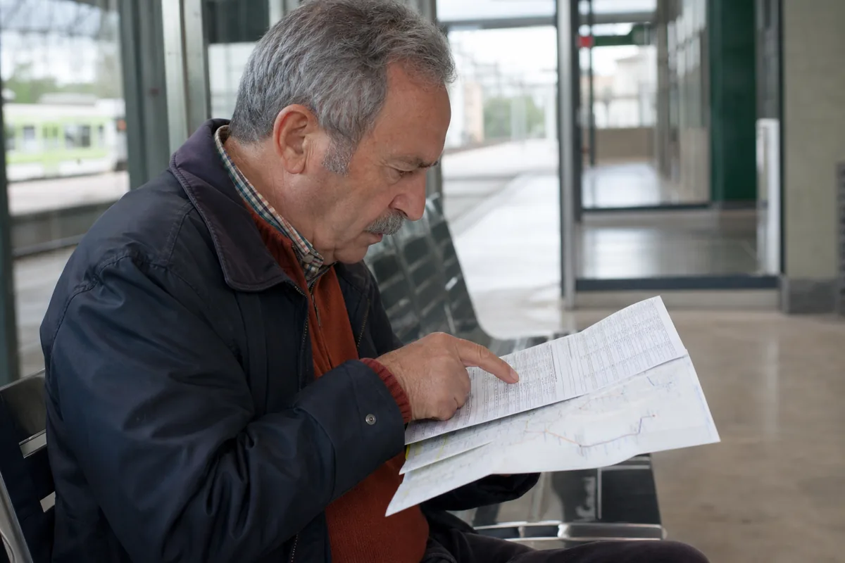 Lector localizando un horario concreto en un folleto de transporte
