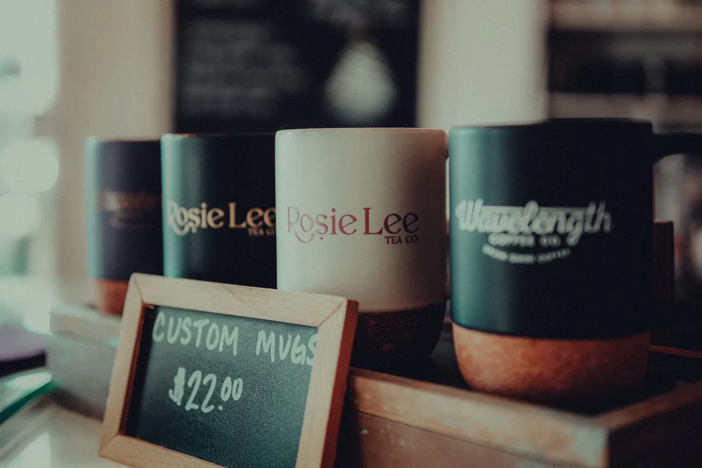 Cómo calcular el precio de productos sublimados 4 Tazas personalizadas expuestas con un cartel de precio